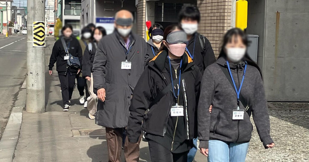 アイマスクを体験しながら歩道を歩く受講生達