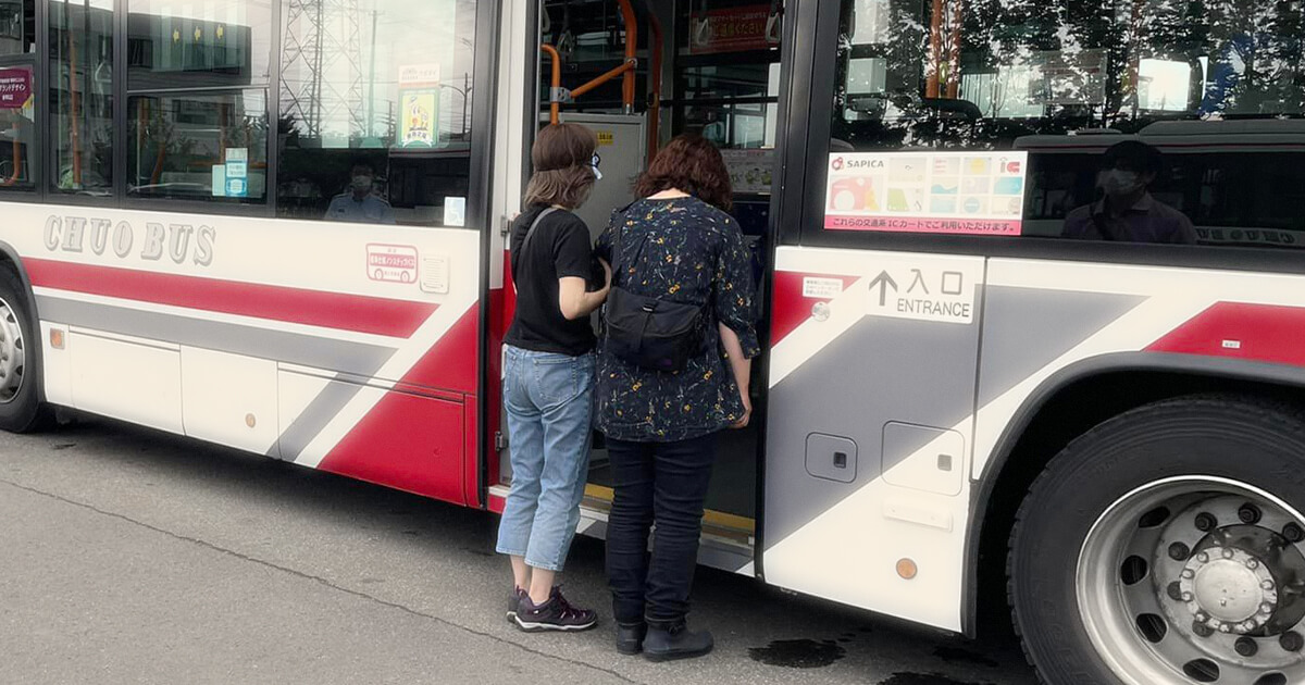 バスに乗り込むのをサポートする女性