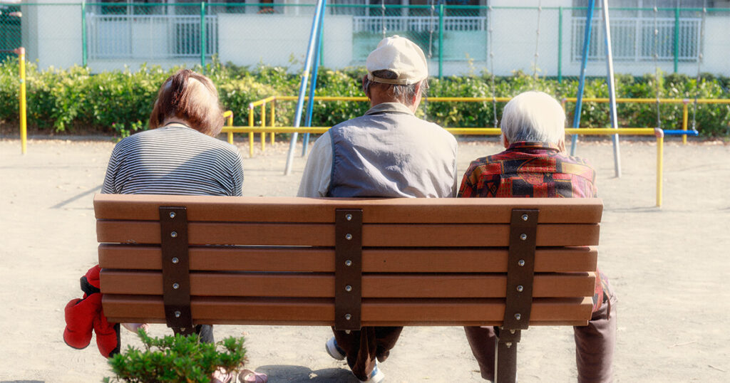 公園のベンチに座る3人の高齢者