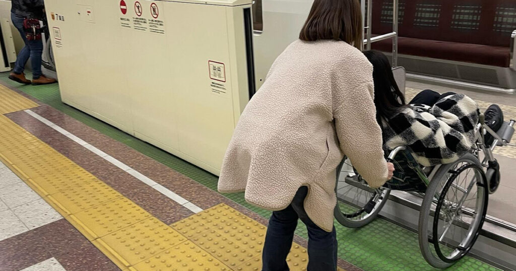 地下鉄に乗り込む車椅子をサポートする女性