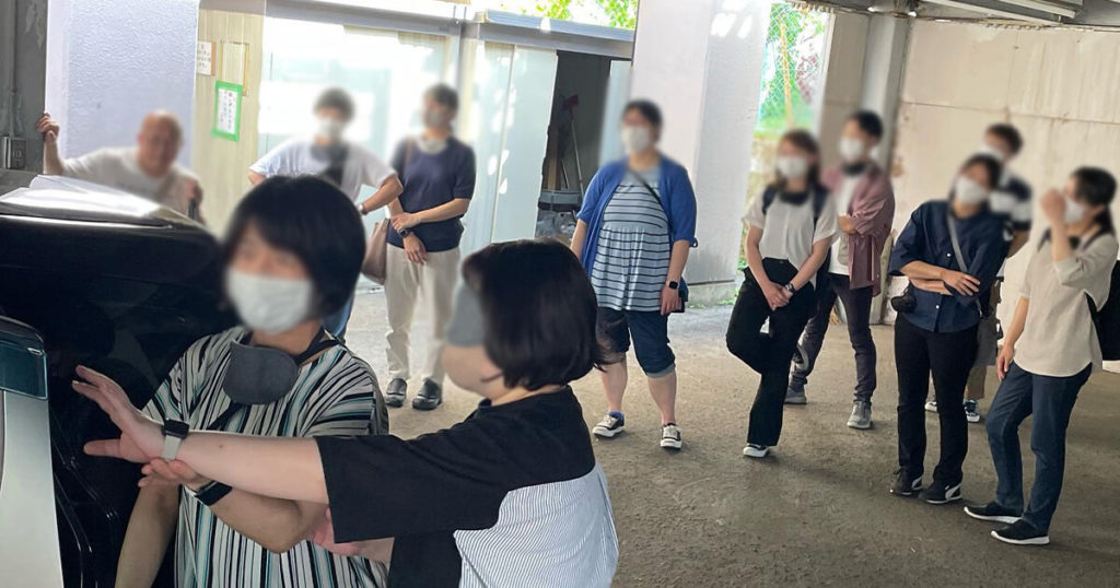 乗用車に乗り込むのをサポートする女性