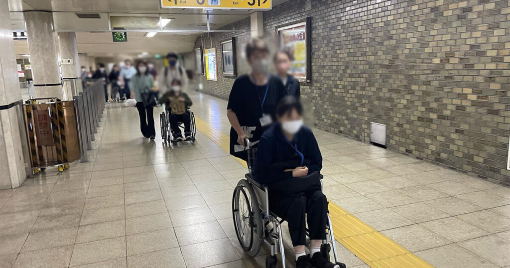 地下鉄構内を車椅子でサポートする女性